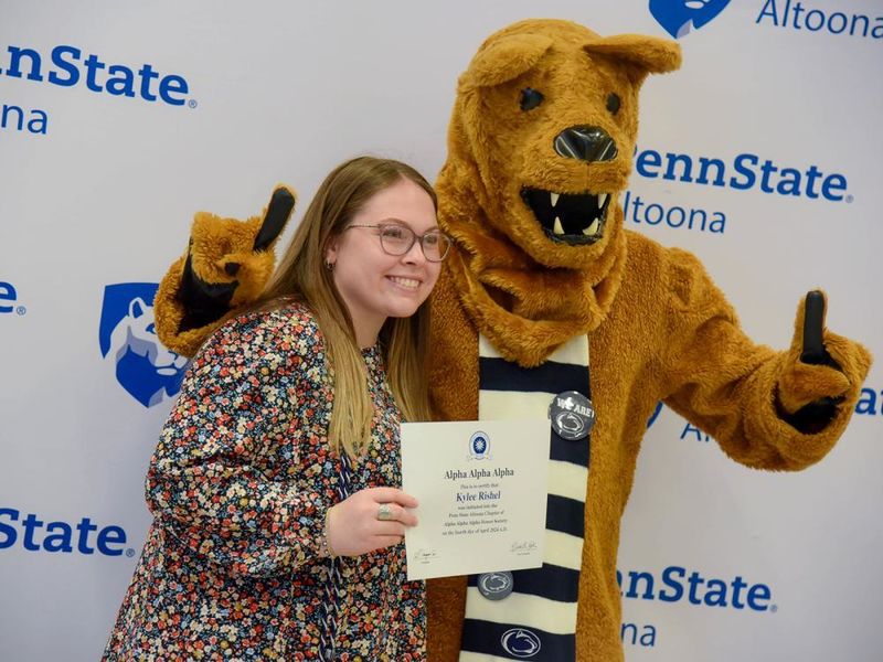 Psychology major Kylee Rishel poses with her certificate and the Nittany Lion after the induction ceremony.